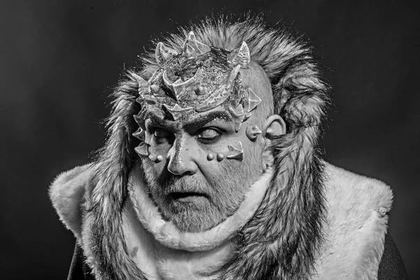 Senior man with white beard dressed like monster. Dark arts concept. Demon on black background, close up. Man with thorns or warts in fur coat. Alien, demon, sorcerer makeup.