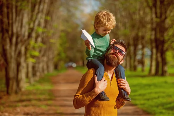 Padre e hijo lanzan avión de papel en el parque, concepto de viaje. Padre e hijo pequeño planean viajar en avión juntos. Nos encanta volar — Foto de Stock