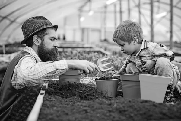 側面ビュー父手フォークで花を植えるための子供を助けること。息子のガーデニングを教えるひげを生やした男。家庭教育概念 — ストック写真