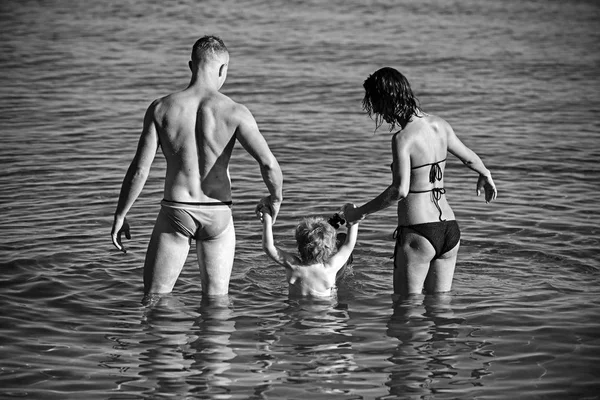Gelukkig kind en ouders spelen in water op het moment van de dag. Concept van vriendelijke familie — Stockfoto