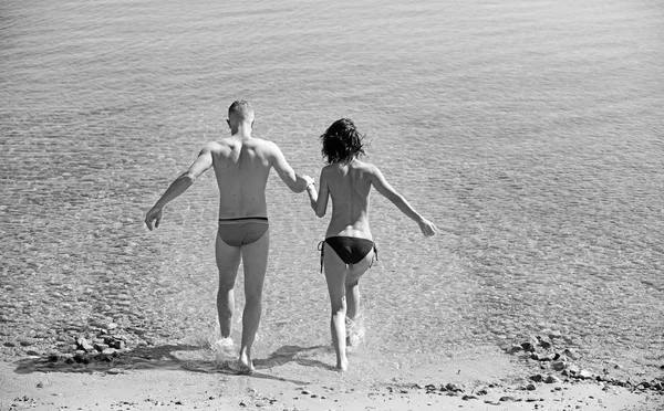 Feliz pareja alegre que se divierten corriendo al mar juntos y haciendo salpicaduras de agua en una playa tropical - concepto sobre vacaciones románticas, luna de miel . —  Fotos de Stock