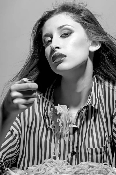 Joven hermosa mujer comiendo espaguetis sobre fondo gris — Foto de Stock