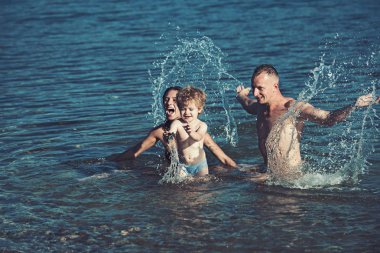 Sevgi ve güven aile değerleri olarak. Anne ve babanın oğlu ile kumsalda denizde yüzmek. Aile Anne ya da babalar gününde çocukla seyahat. Çocuk Anne ve baba ile. Mutlu bir aile tatil yaz.