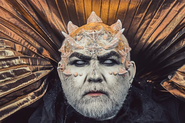 Az ember a tövis, vagy szemölcsök, arca borított csillog. Senior férfi fehér szakállal öltözött monster. Idegen, démon, sorcerer smink. Démon arany gallérral, fekete háttér. Fantasy koncepció. — Stock Fotó