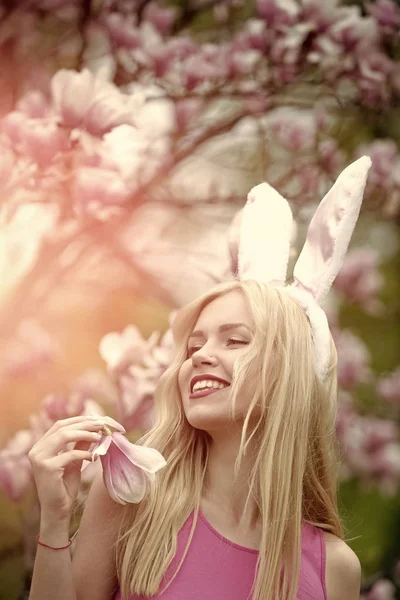 easter, funny woman in glasses and bunny ears at spring magnolia flower.