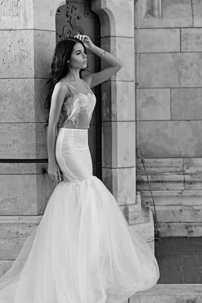 Ragazza sexy in abito bianco con i capelli alla moda. Donna a pietra colonna antica in estate. Moda da sposa e salone di bellezza. Sposa ragazza alla cerimonia di nozze nel castello. Modella o principessa in abito — Foto Stock