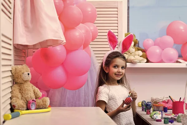 small girl paint handmade egg at party balloons.