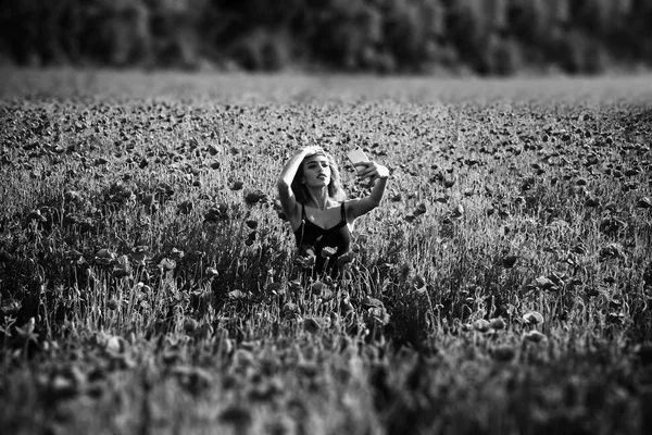 Flower field of red poppy and girl making phone selfie — Stock Photo, Image