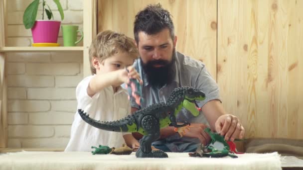 Père et fils jouent avec des jouets. Concept de famille, d'enfance, d'activité et de personnes. Heureux père et petit fils jouant avec des dinosaures jouets à la maison. Jour du père et du fils. Concept d'enfance heureuse . — Video