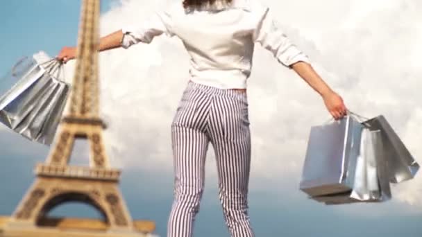 De compras en París, mujer de moda cerca de la Torre Eiffel en Francia. Joven mujer haciendo compras en París. Concepto de tiempo de compras. Hermosa mujer sosteniendo muchas bolsas de compras con la Torre Eiffel en el fondo . — Vídeo de stock