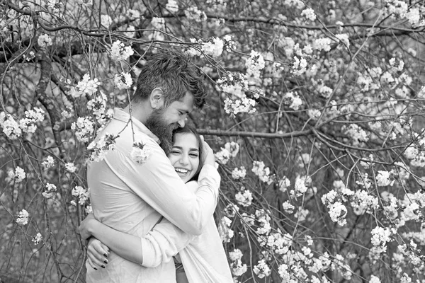 Conceito de data de primavera. Alguns abraços perto de árvores florescentes. Abraços de homem e mulher no jardim florescente no dia de primavera. Casal apaixonado passar o tempo no jardim da primavera, ramos com flores no fundo . — Fotografia de Stock