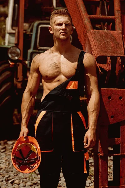 Metal worker. Metal worker rest at heavy machinery. Handsome metal worker in working uniform. Strong metal worker with muscular arms and torso — Stock Photo, Image