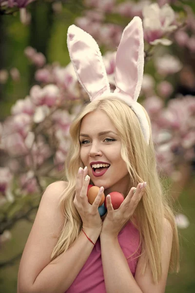 Easter eggs at woman in bunny ears.