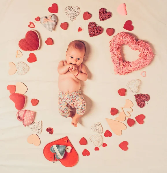 Live in love. Family. Child care. Small girl among red hearts. Sweet little baby. New life and birth. Love. Portrait of happy little child. Childhood happiness.Valentines day