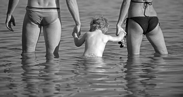 Gelukkige familie - vader, moeder, zoon van de baby in het water langs de zonsondergang zee op strand. Reizen en actieve levensstijl. ouders met kind op zomervakantie. — Stockfoto