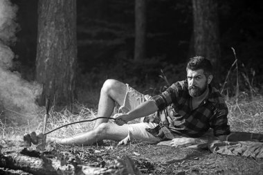 Kamp ve yemek yemek, vintage. Hippi ile sakal kızartma sosis yanıyor. Sakallı adam aşçı gıda şenlik ateşi. Ekose gömlekli adam rahatla doğa üzerinde. Turist kamp keyfini çıkarın. Yaz tatil kavramı