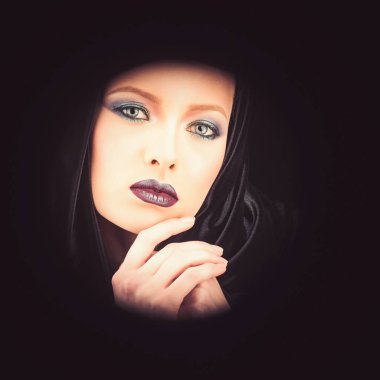 Gotik bir siyah kukuletalı pelerin giyen güzel bir kadın portresi. siyah bir arka plan karşı poz