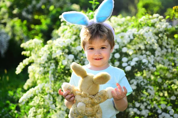 Люблю Великдень. Сімейне свято. Полювання на яйця на весняні канікули. Щасливого Великодня. Дитинство. Маленький хлопчик у зеленому лісі. Кролик з кролячими вухами. Заєць іграшка. Органічне Великодня — стокове фото