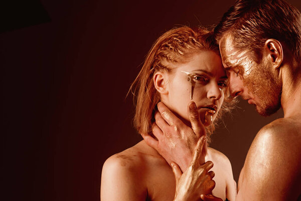 Эротические игры влюблённых пар. Сексуальная пара с золотым макияжем, копировальное пространство. Золотой спа и лечение кожи. Золотая маска и красота коллагена. 24K Gold. Мужские и женские отношения
