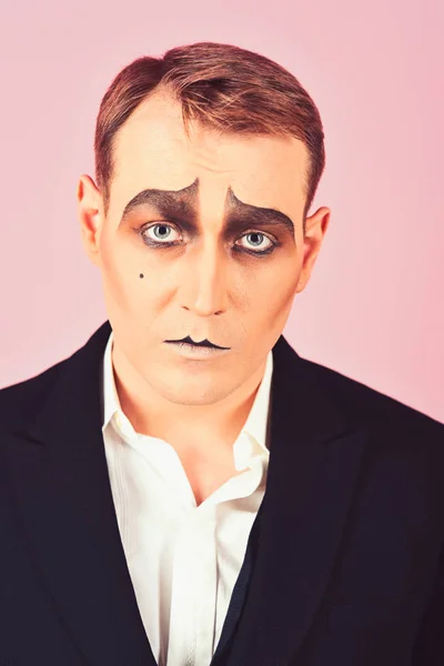 Tragical actor. Man with mime makeup. Mime artist. Mime with face paint. Theatre actor miming. Stage actor miming. Theatrical performance art and pantomime. Comedian or tragedian performer