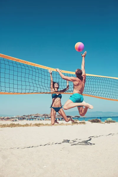 Les gens qui jouent au beach-volley s'amusent dans un mode de vie sportif et actif. Homme frappant volley ball dans le jeu en été. Femme et homme modèle de fitness mode de vie sain faire du sport sur la plage — Photo