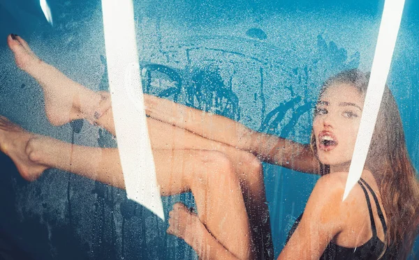 Mode en beauty. Regen druppels op vensterglas met gezicht meisje. Spa-behandeling, douche en hygiëne. Sexy vrouw achter plastic folie met water druppels. Venster met water druppels voordat meisje met make-up — Stockfoto