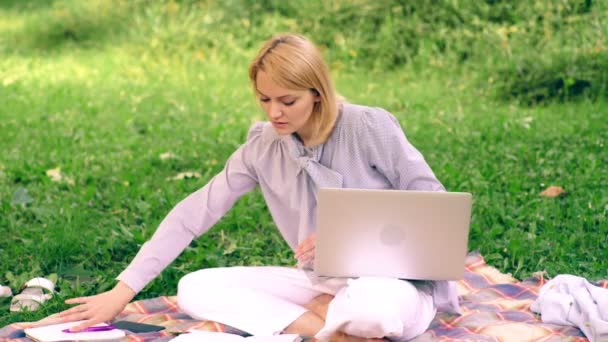 Naturalne środowisko biurowe. Świadczenia pracy na zewnątrz. Kobieta z przenośnego komputera pracy na zewnątrz. Edukacja koncepcja technologii i Internetu. Dziewczyna praca z laptopem w parku siedzą na trawie. — Wideo stockowe