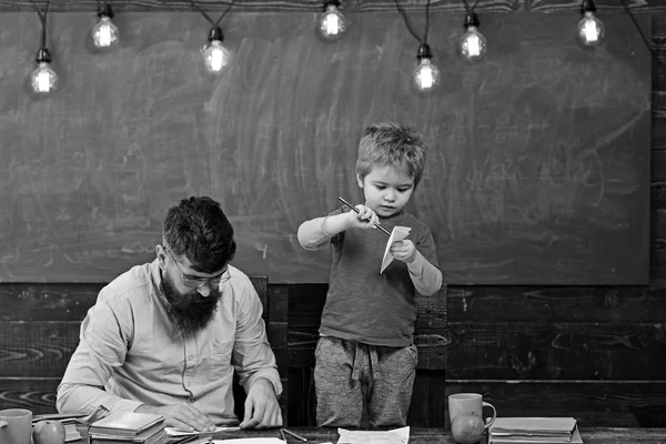 Familie vrijetijdsbesteding. Vader en leuke zoon papier vliegtuigen maken. Ontwikkelen van de creativiteit van de kinderen — Stockfoto