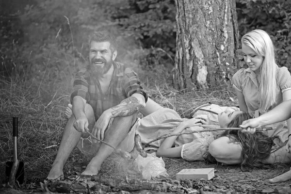 Gülümseyen adam ile kamp ateşi üzerinde sosis pişirme kolundaki dövme sakallı. Orman, dostluk ve doğa kavramları piknik arkadaşlar — Stok fotoğraf