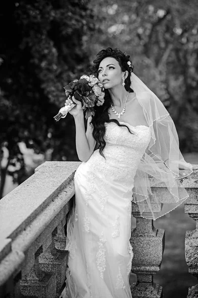 Novia en vestido blanco de moda y velo. Mujer sensual con ramo de bodas. Mujer con flores en el balcón. Chica de belleza con maquillaje nupcial y peinado. Moda de boda y moda — Foto de Stock