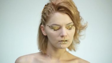Altın boya damlar ağzından seksi dudaklarından damlayan lipgloss güzel model kızlar ağız, altın metalik cilt makyaj altın sıvı bırakır. Güzellik kadını yüz makyaj yakın çekim.