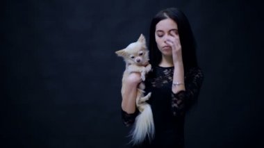 Elleri üzerinde bir köpek ile kız. İki arkadaş portresi. Siyah elbiseli kadın köpek ellerinin izole siyah bir arka plan üzerinde tutar. Köpek insan dostudur.
