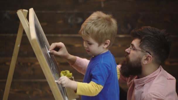 Father and son are painted with chalk on a board. Happy father teaches his son to draw on wooden background. Fathers day concept. Father and son. Happy loving family. I love you, dad. — Stock Video