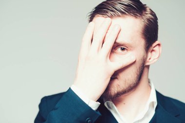 Sarışın model gri arka plan üzerinde izole. Sakallı adam ve onun yüzünü palm ile kapsayan ela gözlü