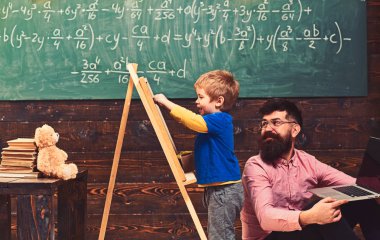 Küçük öğrenci sınıfta gülümseyen öğretmen ile. Yan görüntülemek sevimli küçük çocuk kara tahta üzerinde yazılı. Erken öğrenme kavramı