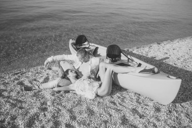 Güneşli yaz gününde, deniz yüzeyi arka planda Kano yakınındaki plajda aşık çift tekne. Maço gövde ile Sahil kız ile boş zaman harcamak. Tatil kavramı. Çift tatilde, resort rahatlatıcı