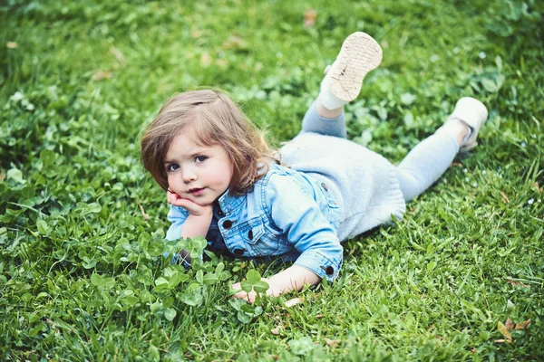 Pequeña chica encantadora se encuentran en la hierba verde — Foto de Stock