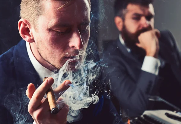 Thinking about problem solution. Thoughtful man smoking cigar. Businessmen hold business meeting. Business partners thinking together in office. Coworkers solving a business problem