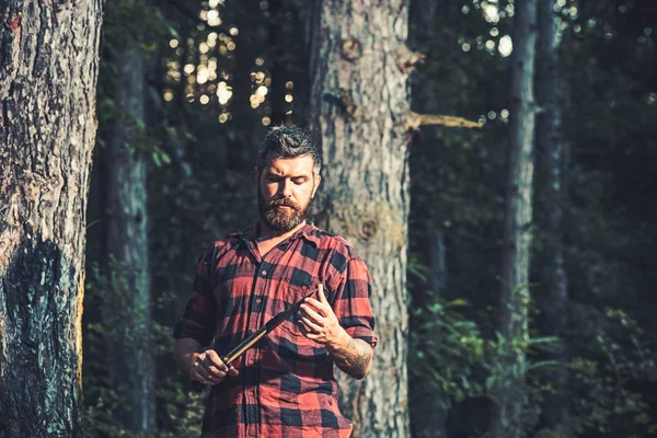 Brutala lumberjack tittar på små vassa spade i hans händer. Lone vandrare i skogen. Sommar natt camping — Stockfoto