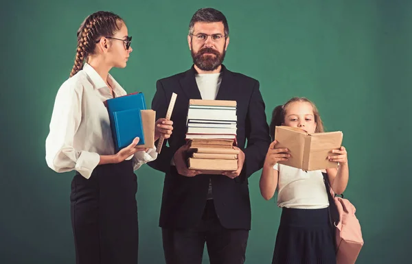 School time of sisters and father in library. Literature lesson and reading grammar book. Education in knowledge day. Teacher man and girls hold book pile at school. Back to school and home schooling — Stock Photo, Image