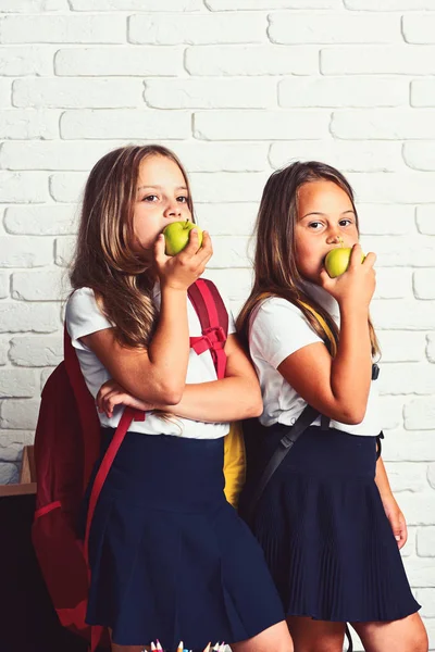 Powrót do szkoły i szczęśliwy czas dzieci słodkie jedzenie jabłek. Dzieci uczą się w klasy na tle ściany z cegieł — Zdjęcie stockowe