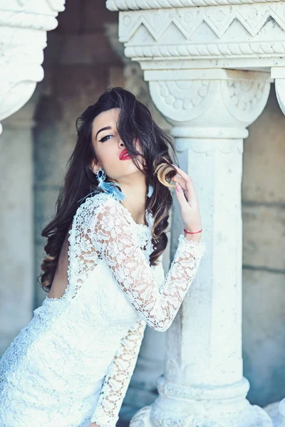 Woman with long brunette hair. Sensual woman pose at column. Bride with makeup face, look. Fashion girl in white dress, vogue. Beauty model with glamour makeup — Stock Photo, Image