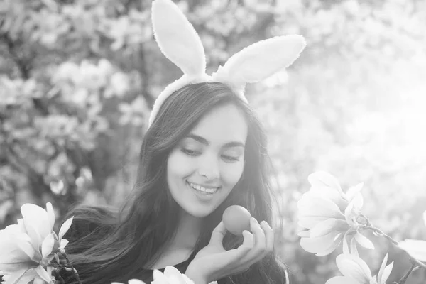 Menina com ovo de Páscoa, em orelhas de coelho, magnólia — Fotografia de Stock