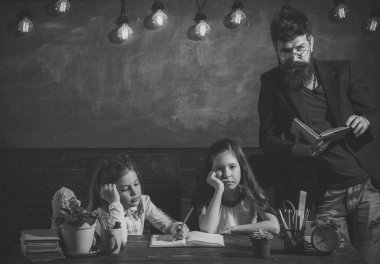 Sıkıcı ders kavramı. Öğretmen ve kız öğrencilerin sınıfta, kara tahta arka plan. Sakallı adam kız öğrenciler, kitap okuma öğretir. Bıkkın ve yorgun çocuk öğretmen dinleme.