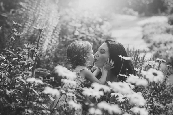 Woman and child kiss on sunny floral landscape