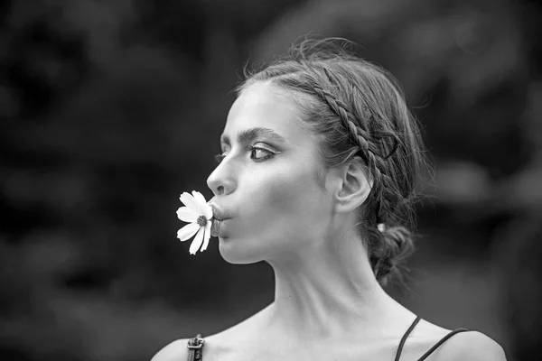 Woman with daisy flower in mouth