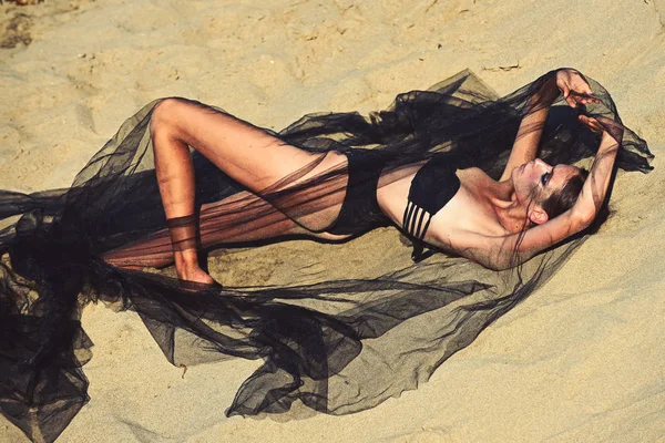 Mode kvinna i baddräkt under svart slöja koppla av på sanden — Stockfoto