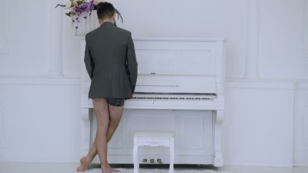 白い背景の上にジャケットとパンツの演劇ピアノの男。リアビュー。才能のあるミュージシャンのコンセプトです。ピアニストの音楽を求めて. — ストック動画