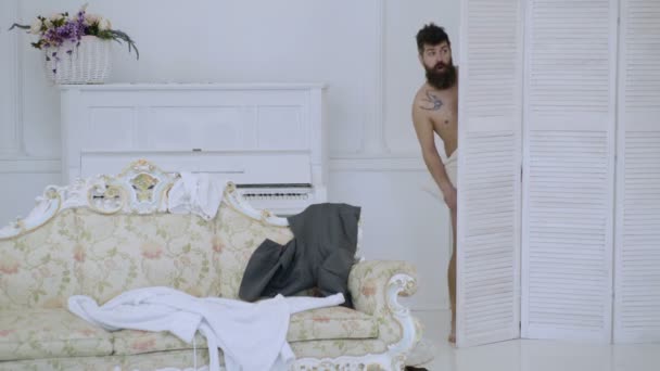 Homme, amant à l'intérieur blanc pris nu. Concept d'amoureux passionnants. Hipster nu sur le visage choqué détecté de manière inattendue dans la chambre. Homme avec barbe et moustache se cachant derrière un écran pliant . — Video