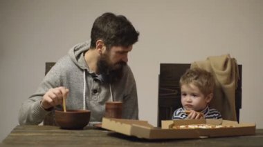 Babası yulaf lapası daha lezzetli pizza çocuk ikna eder. Bir çocuk parça pizza tutar ise adam yulaf lapası karışımları. Sağlıklı gıda kavramı. Sabah kahvaltı kavramı. Sağlıklı ve fast food.